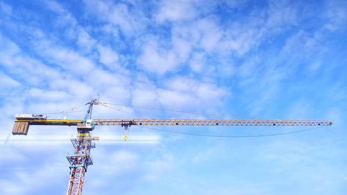 Low angle view of crane at construction site against sky