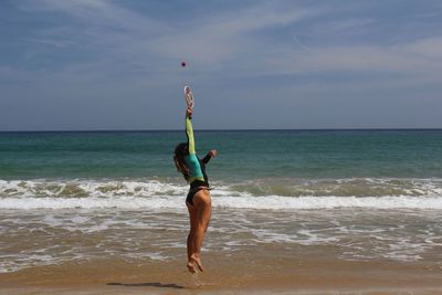 Full length of woman playing tennis on beach