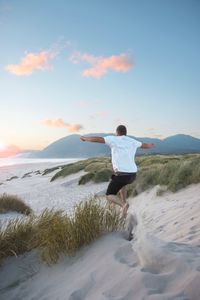 Man jumping on beach against sky