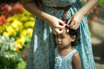 Midsection of woman attaching hair clip on daughter hair