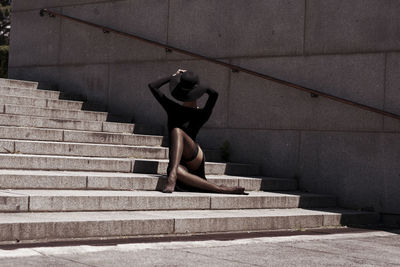Full length of young woman wearing hat sitting on steps