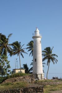 Lighthouse on beach against blue sky