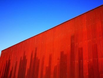 Low angle view of cargo container against clear blue sky