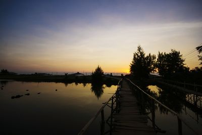 Pier on lake at sunset