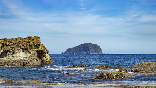 Rocks on sea shore against sky