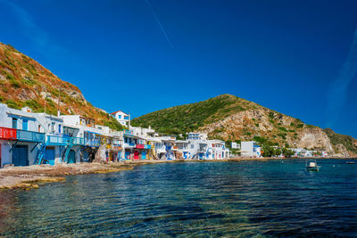 Houses by sea against blue sky