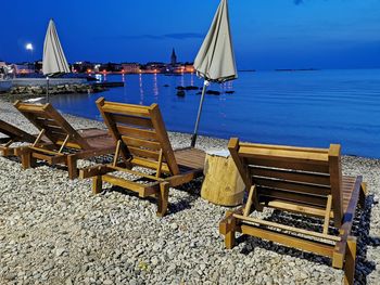 Deck chairs on beach against blue sky