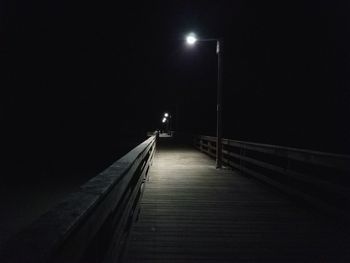 Footbridge on illuminated street light at night