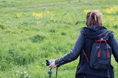 Rear view of woman with backpack standing on field