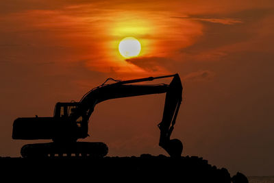 Silhouette construction site against sky during sunset