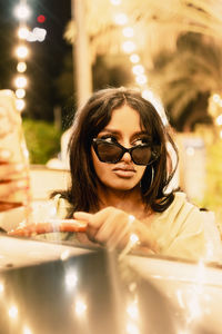 Portrait of a young woman wearing sunglasses and driving a convertible car