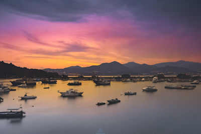 Sailboats in sea against sky during sunset