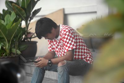 Rear view of man using mobile phone outdoors