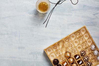 Still life of box of opened chocolates, whisky glass, necklace