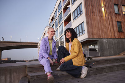 Young women sitting and talking together, block of flats in background