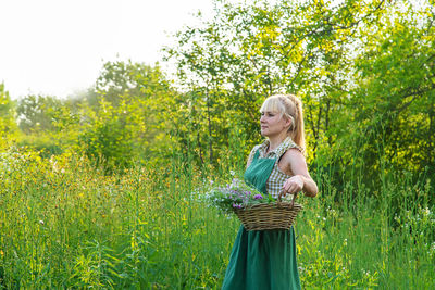 Portrait of smiling young woman standing against plants