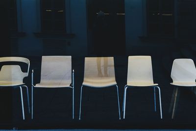 Empty chairs seen through glass window at store for sale