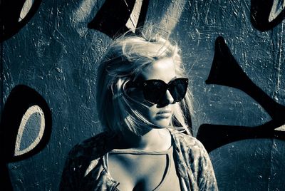 Close-up of woman in sunglasses against graffiti wall