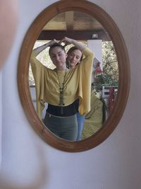 Portrait of young woman standing with reflection in glass