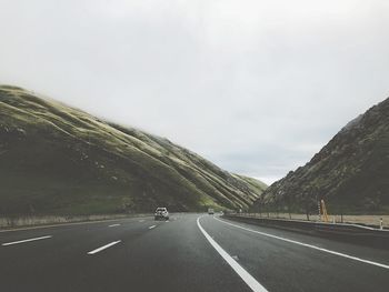 Road by mountain against sky