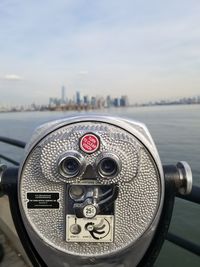 Close-up of coin-operated binoculars against cityscape