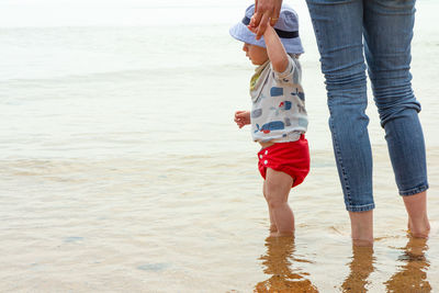 Low section of mother and daughter on beach