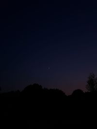 Low angle view of silhouette trees against clear sky at night