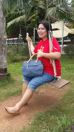 Young woman sitting on grassland against plants