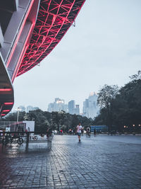 People walking on footpath by buildings in city