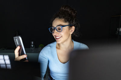 Smiling businesswoman using smart phone at home office