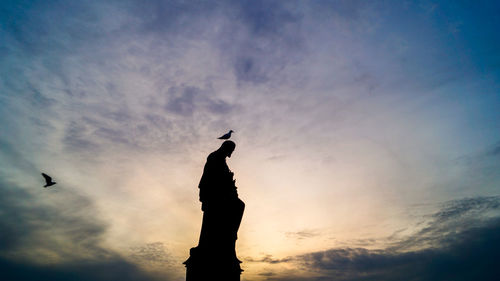 Low angle view of silhouette man standing against sky during sunset