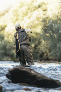 Rear view of man fishing in river