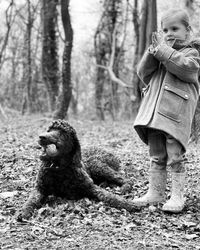 Girl standing by dog in forest