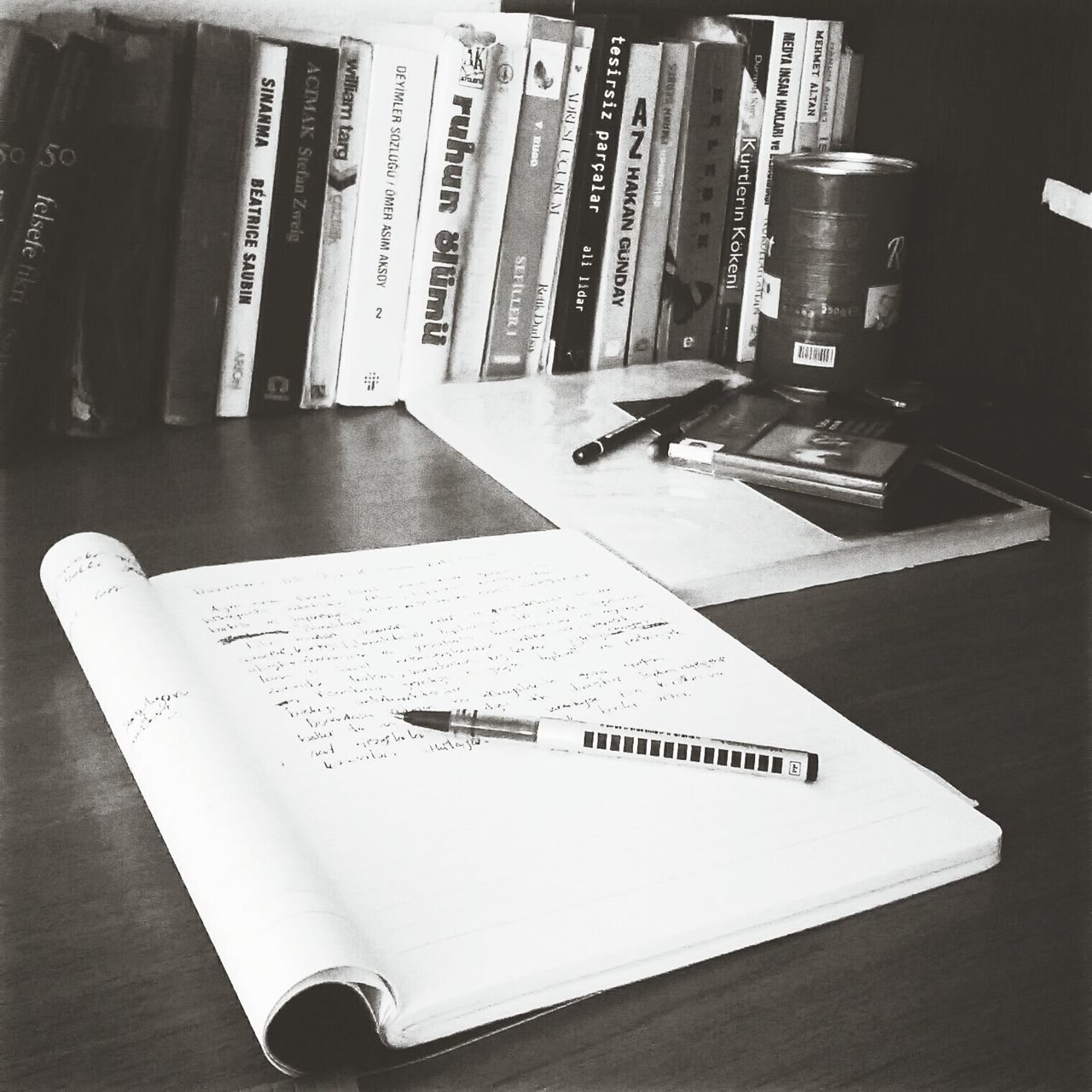 indoors, table, communication, book, text, still life, high angle view, paper, education, technology, western script, pen, close-up, desk, no people, document, laptop, page, wood - material, home interior