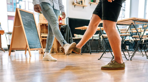 Low section of men touching legs standing on hardwood floor