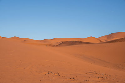 Amazing view of brown sand dunes in desert against clear blue sky