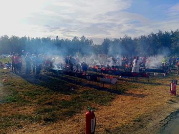 Rear view of people on field against sky