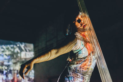 Woman dancing by transparent curtain in darkroom