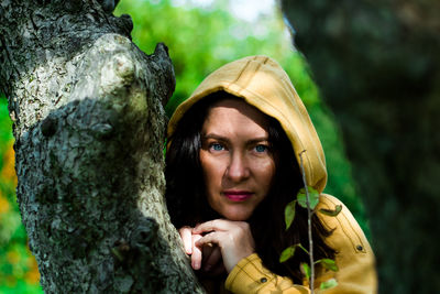 Portrait of woman holding tree trunk