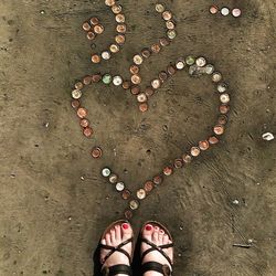 Directly above shot of womans feet near heart shape made with bottle caps
