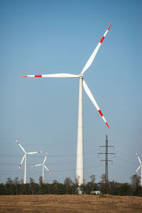 Wind turbines on field against sky