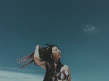 Low angle view of woman looking up against sky