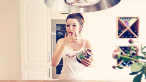 Portrait of woman holding chocolate container in kitchen at home