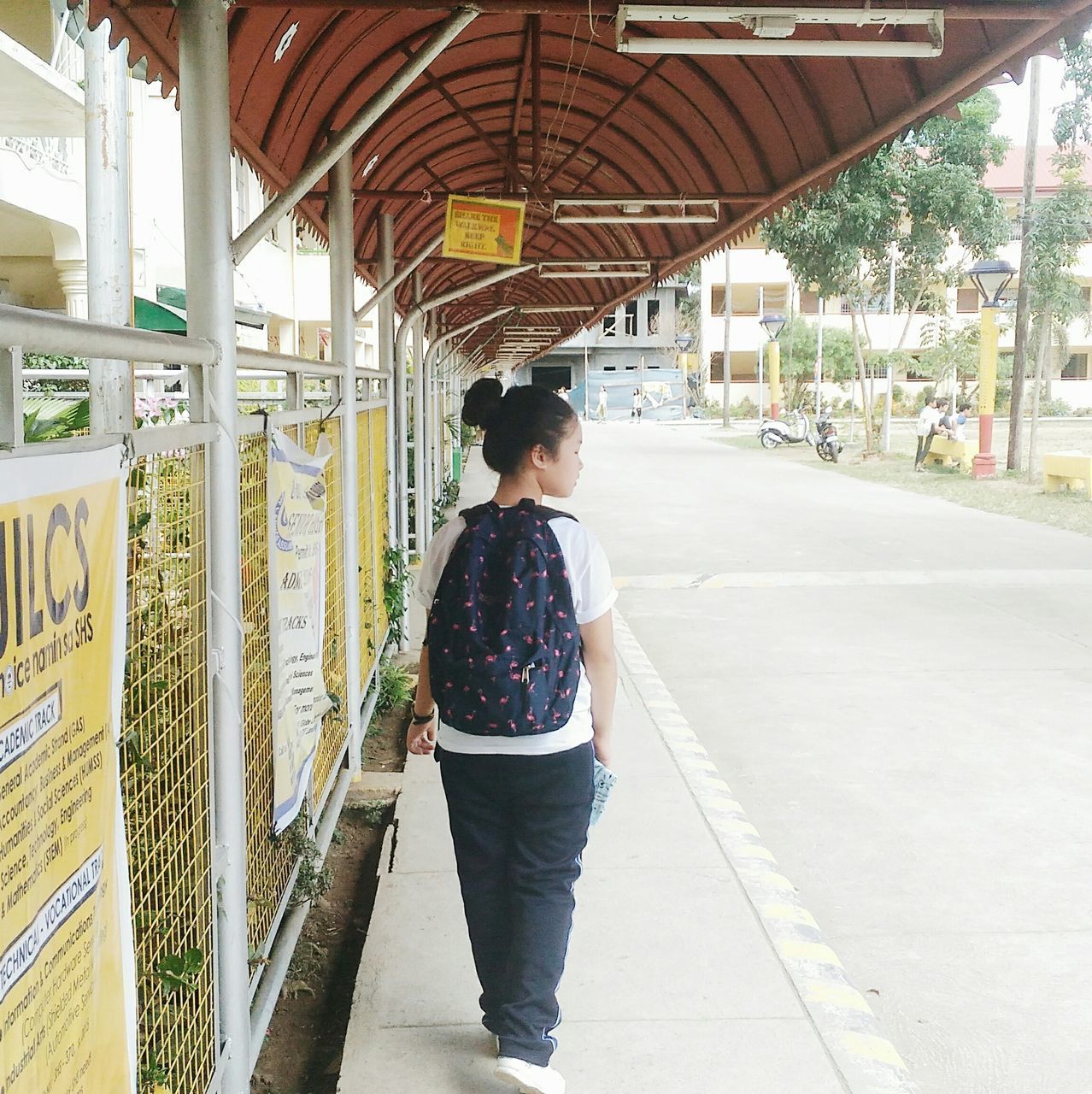 REAR VIEW OF WOMAN WALKING ON RAILWAY STATION