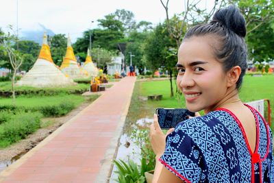 Portrait of smiling young woman using smart phone outdoors