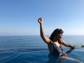 Young woman swimming in sea against clear sky