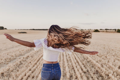 Woman with arms raised on field against sky