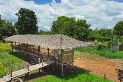 Built structure on field by trees against sky