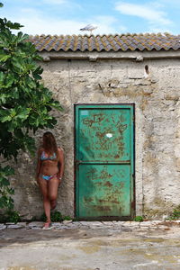 Woman standing against door of building