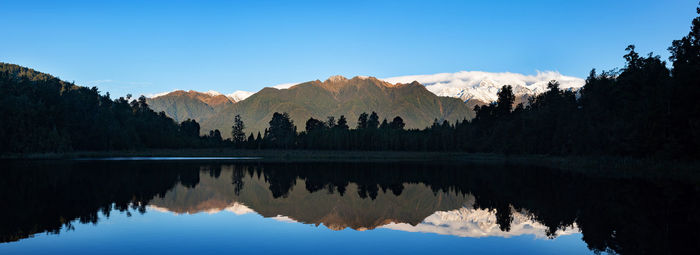 Reflection of trees in lake against blue sky